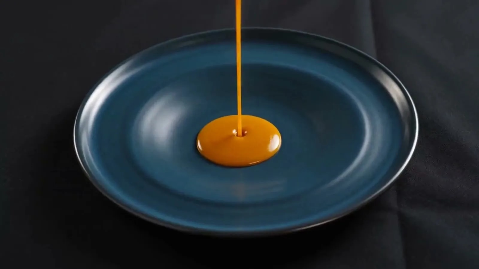 Salsa ámbar cayendo sobre un plato de vidriado cobalto