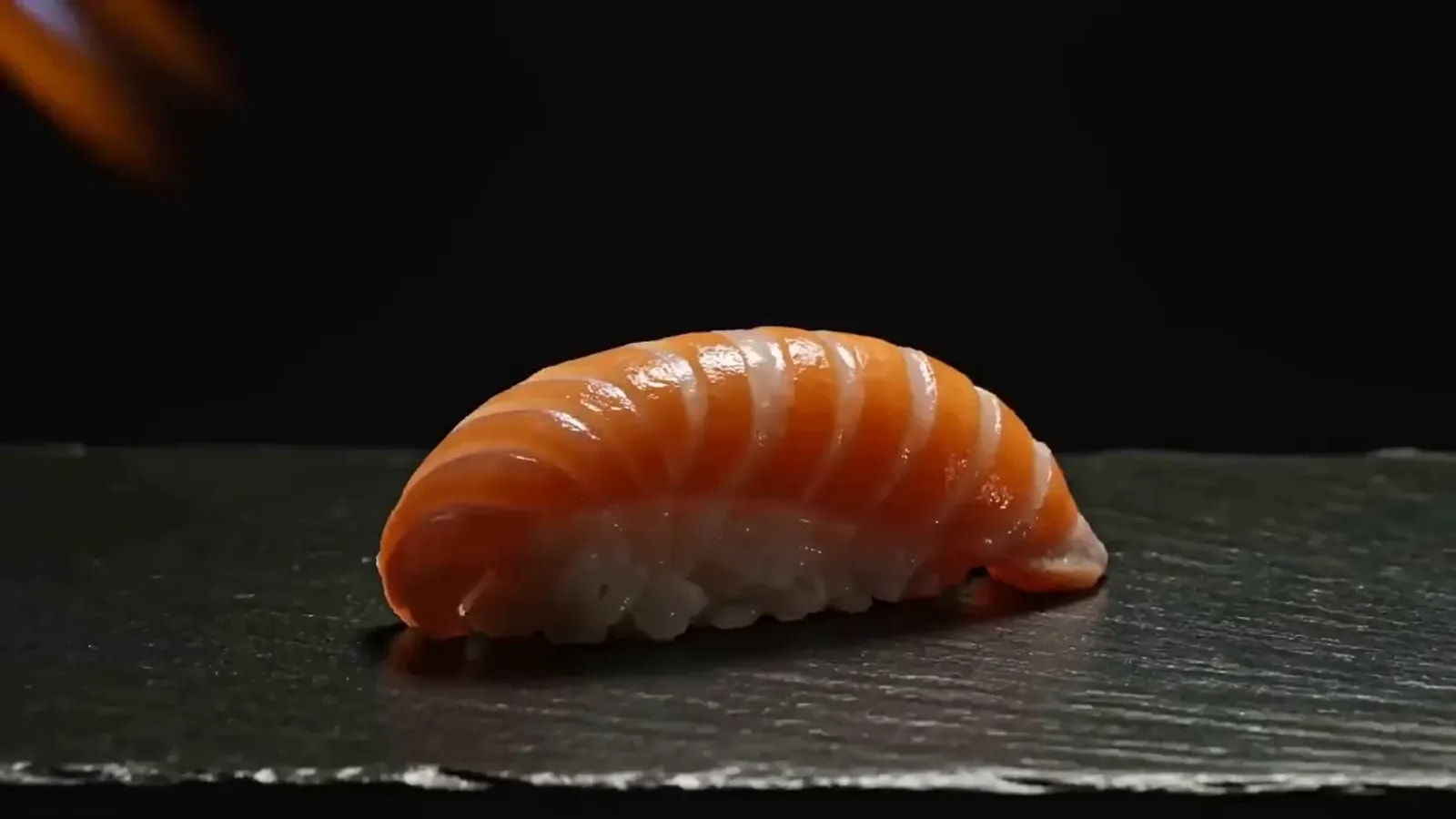Nigiri de salmón flameado con soplete sobre piedra negra