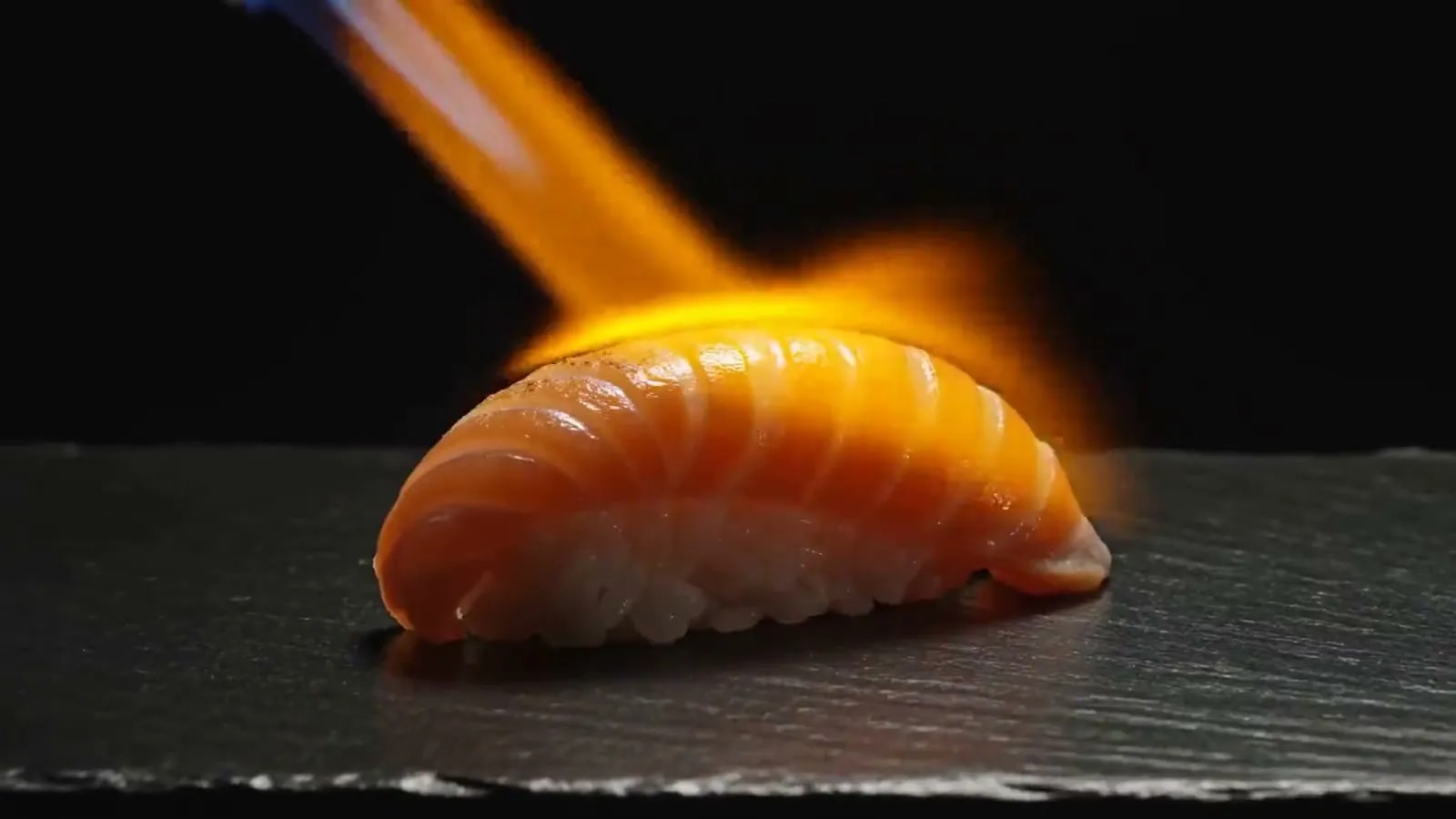 Nigiri de salmón flameado con soplete sobre piedra negra
